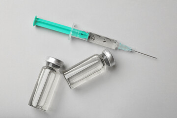 Hepatitis vaccine in glass vials and syringe on grey background, flat lay