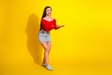 Young woman in casual summer outfit on yellow background showcasing cheerful gesture, style, and dynamic energy