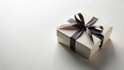 Fototapeta premium A delicately presented gift box, adorned with a sleek black ribbon, awaits its recipient.