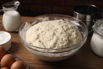 Raw dough and ingredients on wooden table, closeup