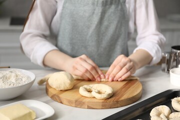 Woman shaping pretzels at table in kitchen, closeup