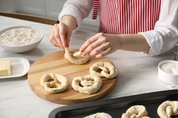 Woman shaping pretzels at table in kitchen, closeup