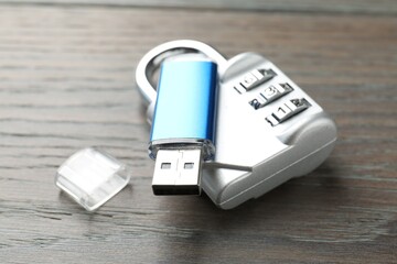 Flash drive and combination padlock on wooden background, closeup