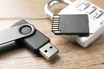 Flash drive, SD memory card and combination padlock on wooden background, closeup