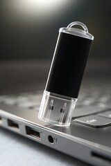 Flash drive and laptop on gray table, closeup