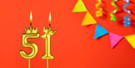 Number 51 candle - Birthday celebration on an orange background with pennants