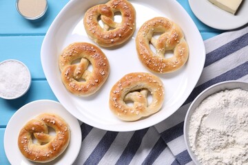 Tasty pretzels and ingredients on light blue wooden table, flat lay