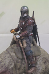 Naklejka premium GUAYAQUIL, ECUADOR - AUG 06, 2023: Collectible figure of The Mandalorian riding a creature, displayed in a geek store. The character belongs to the Star Wars universe and the popular Disney+ series.