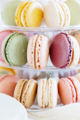 Fresh macarons in a three-tiered tray on a festive table.