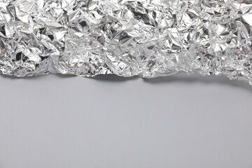 Piece of crumpled aluminum foil on light grey background, top view. Space for text