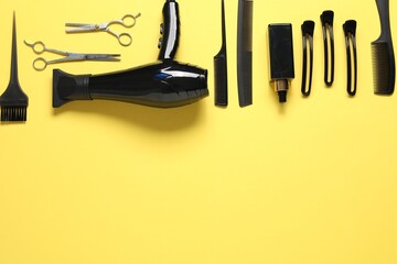 Different hairstyling tools on yellow background, flat lay. Space for text