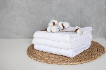 Clean towels and cotton flowers on white table indoors, closeup. Space for text