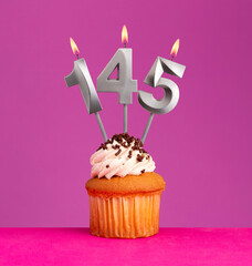 Birthday candle number 145 with cupcake on violet background