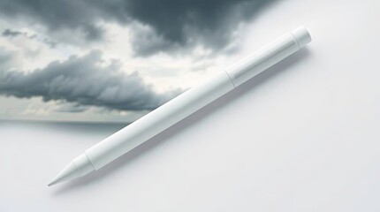 Naklejka premium A light gray writing instrument rests on a white surface beside a somber sky image.