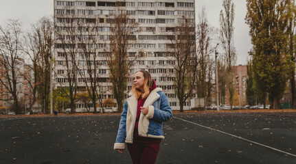 A young woman explores an urban park during an overcast day, surrounded by towering buildings and...
