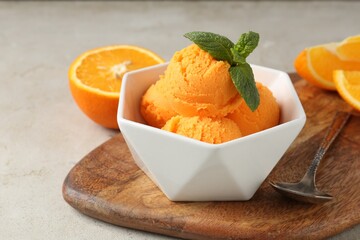Balls of tasty orange sorbet, fresh fruit, mint and spoon on light table, closeup
