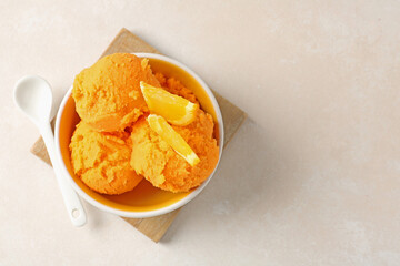 Tasty orange sorbet, fresh fruit and spoon on light table, top view. Space for text