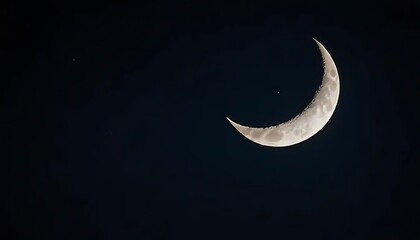 Crescent moon shining brightly in a dark night sky with a single visible star in the distance