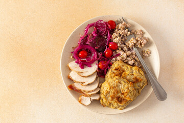 A healthy meal of green buckwheat with chicken breast, zucchini pancakes, fermented vegetable salads
