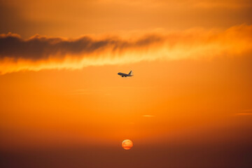Fototapeta premium Silhouette airplane flying against orange sky during sunset background. 