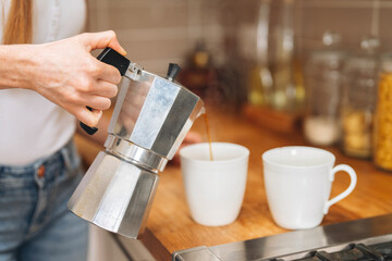 Preparing fresh coffee in kitchen setting with two white cups on a wooden countertop