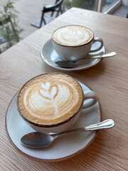 Two cups of cappuccino coffee stand on the table.