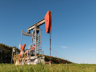 Operating oil and gas well in oil field, profiled against the blue sky