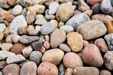 Natural composition of smooth multi-colored stones on a beach. Close-up shot of various rounded pebbles and rocks in earthy tones, forming a vibrant and textured surface.