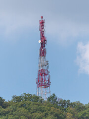 Directional antenna array on a red and white communication tower against sky
