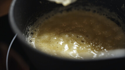 Female chef preparing bechamel sauce, stirring in bowl.