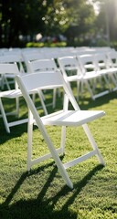 White resin chairs arranged neatly on grass for outdoor wedding ceremony seating