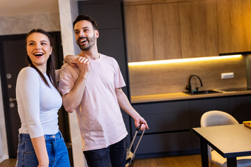 Young couple comes into the apartment for their vacation. They carry the baggage with them.