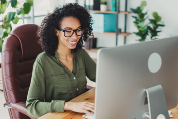 Smiling professional businesswoman working on a computer at a modern office with natural daylight...