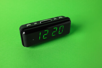 Digital alarm clock showing 12:20 o'clock on green background