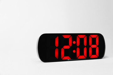 Digital alarm clock showing 12:08 o'clock on grey background