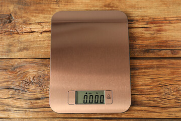 Modern electronic kitchen scale on wooden table, top view
