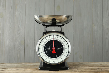 Mechanical kitchen scale with bowl on wooden table