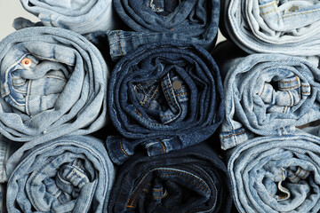 Different stylish rolled jeans as background, top view