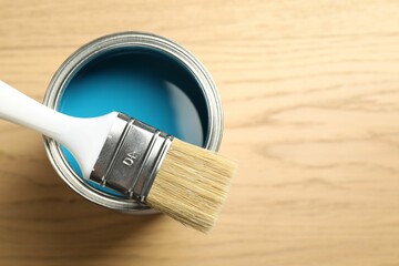 Can of light blue paint and brush on wooden background, top view. Space for text
