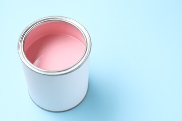 Can of pink paint on light blue background, closeup. Space for text