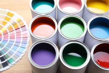 Cans of bright paints and color palettes on wooden table, closeup