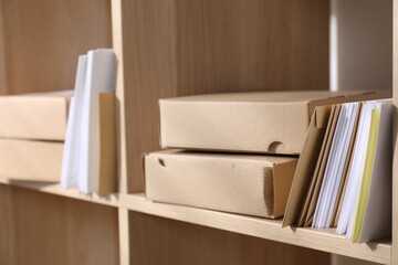 Different paper envelopes on wooden shelves in post office, closeup