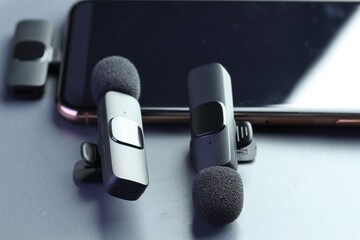 Lavalier microphones and smartphone on light grey background, closeup