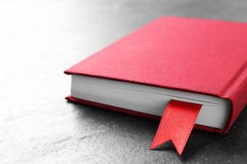Book with red ribbon bookmark on dark textured table, closeup
