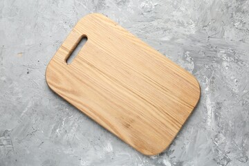 One wooden serving board on light grey textured table, top view. Space for text
