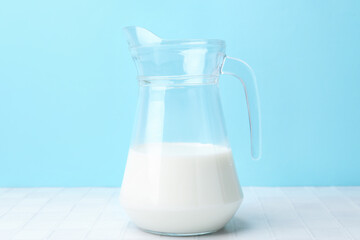 Fresh milk on white table against light blue background