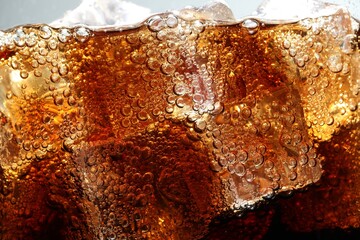 Refreshing cola with ice as background, macro view