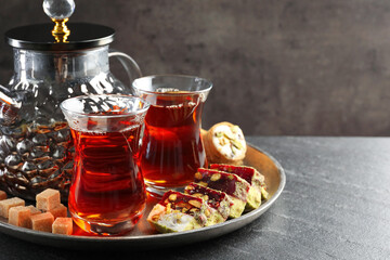 Tasty Turkish tea and delight on black table. Space for text