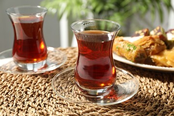 Traditional Turkish tea in glass cups and sweets on table, closeup