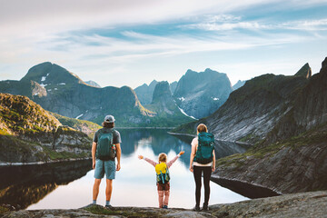 Family traveling in Norway parents hiking with child in Lofoten islands active summer vacations outdoor. Father, mother and kid backpacking in mountains enjoying lake landscape, healthy lifestyle tour
